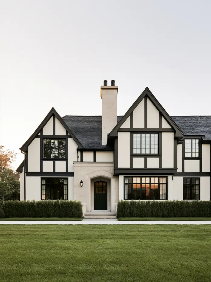 Modern Tudor house exterior with white stucco, black half-timbering, black steel windows and a stone entry