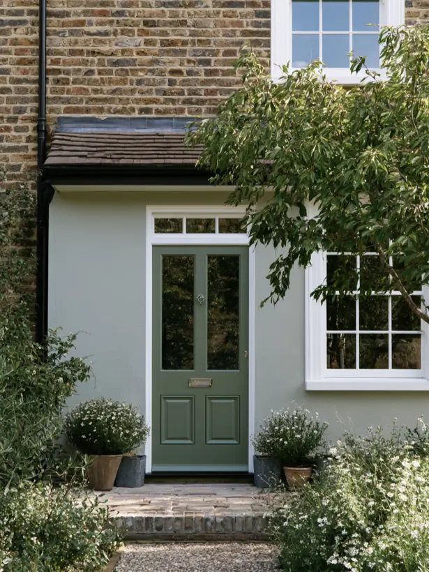 Sage green front door on a pale sage green house exterior with white trim and brick
