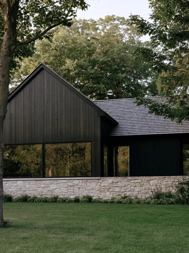 Black timber gable house exterior with dark shake roof set on a pale rough stone base