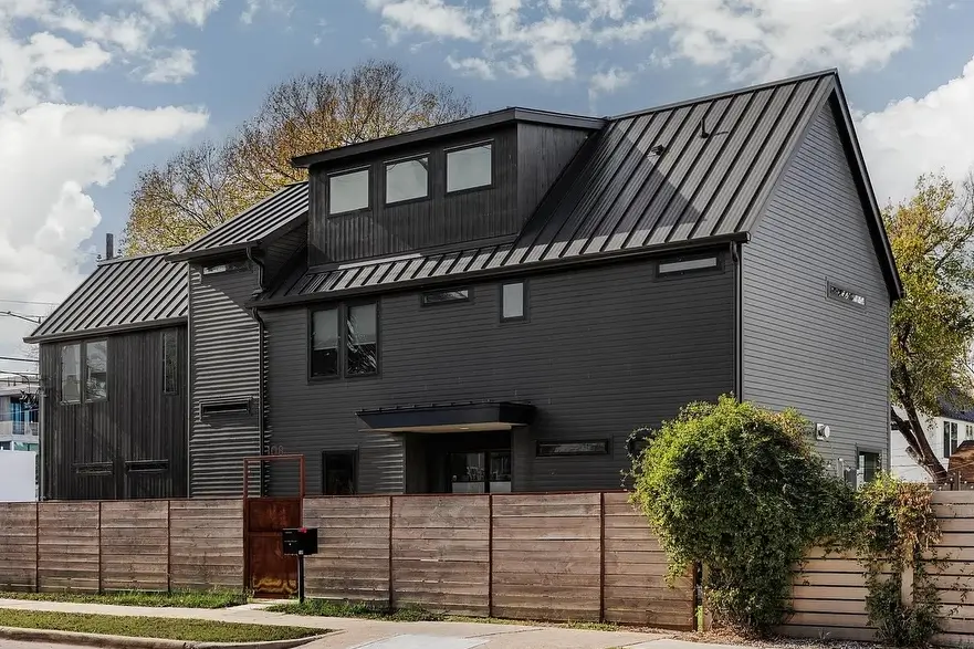 All-black house exterior with mixed siding, standing-seam roof, corten steel mailbox and horizontal wood fence