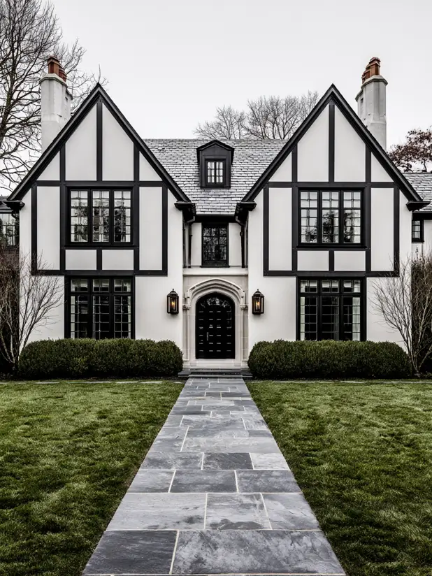 Symmetrical white-and-black modern Tudor with a bluestone walk and paired lanterns