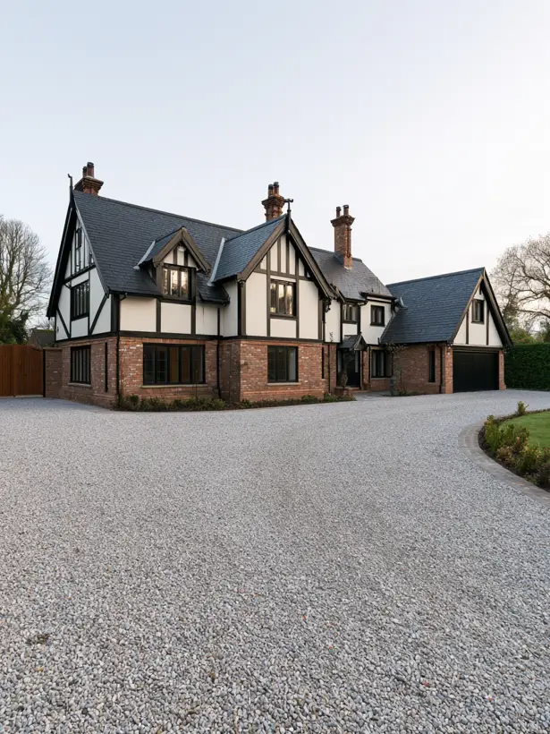 Red brick modern Tudor with cream stucco gables and black windows on a green summer lot